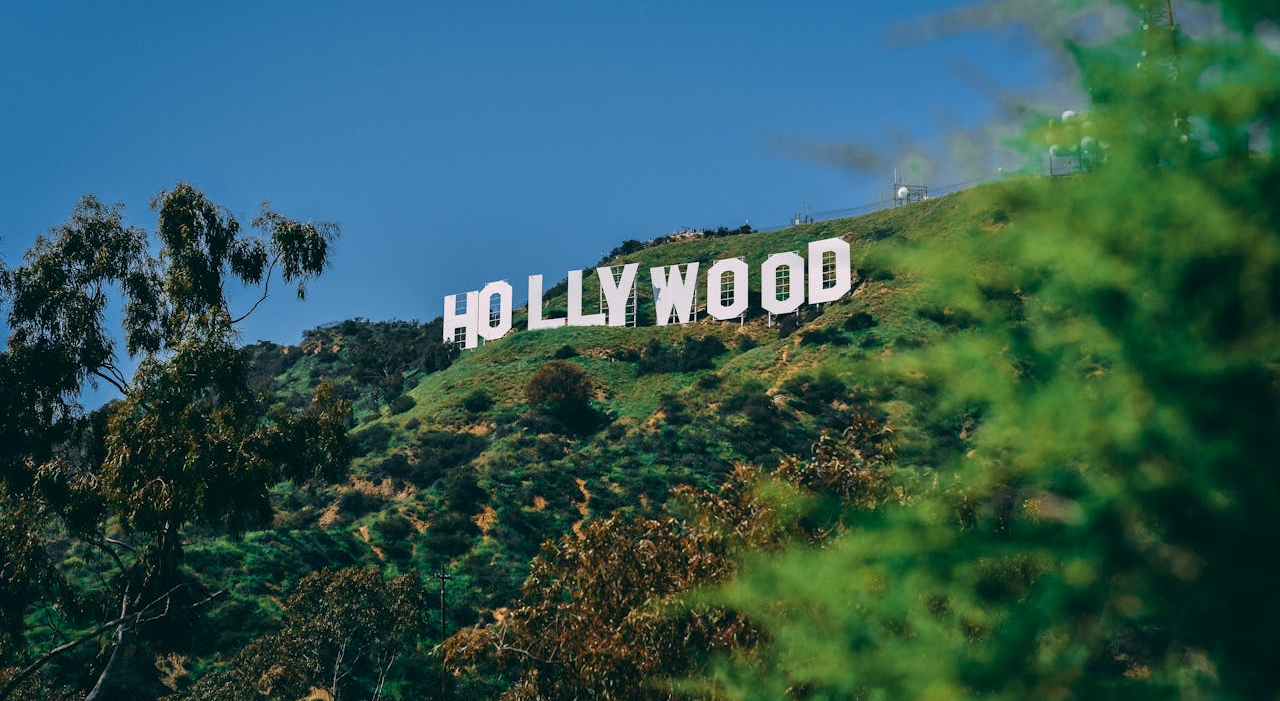 Gateway to Hollywood The historic Hollywood Sign on a lush green hillside under a clear blue sky.