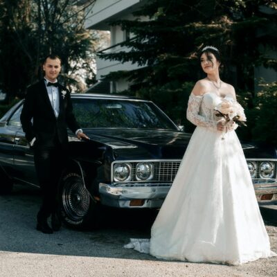 Elegant bride and groom stepping out of a luxury black car, holding her bouquet in a wedding setting.