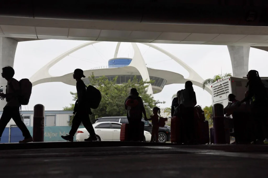 Crowded terminal walkway at Los Angeles International Airport with Theme Building in background, ideal for private LA VIP Car Service airport pickups.