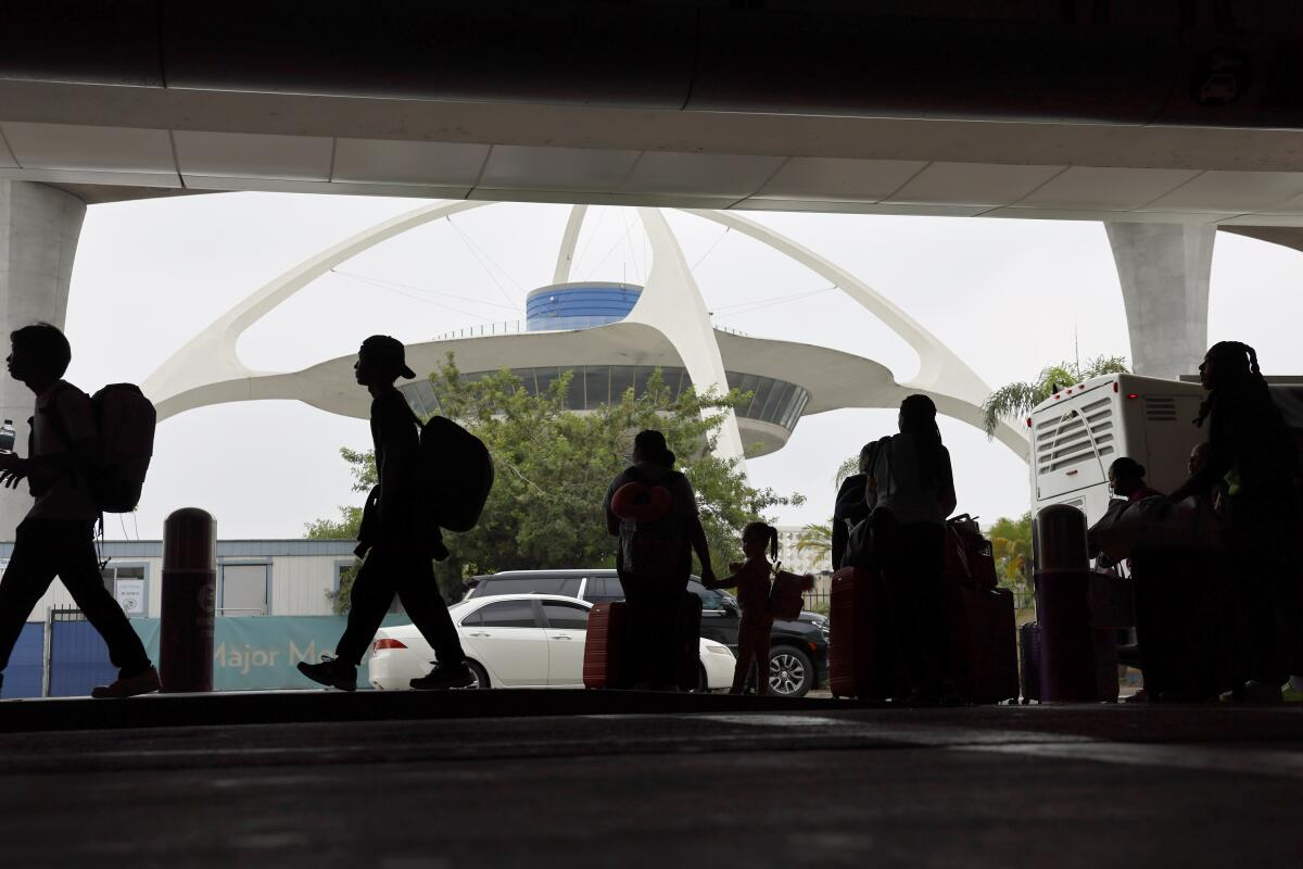 Crowded terminal walkway at Los Angeles International Airport with Theme Building in background, ideal for private LA VIP Car Service airport pickups.